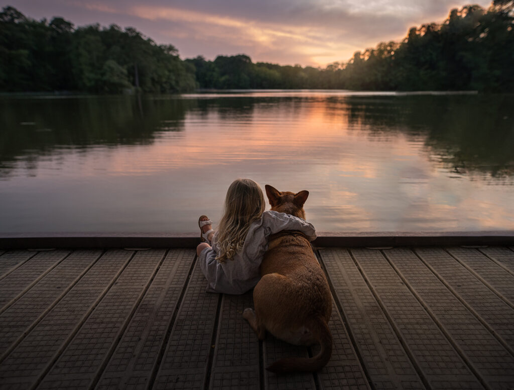 Girl and her dog at a dock during sunset