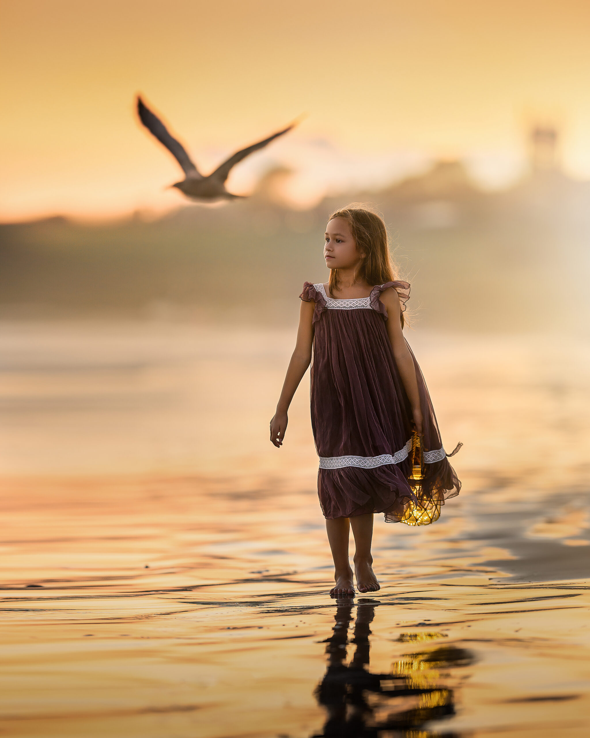 Girl walking along the beach with a seagull flying